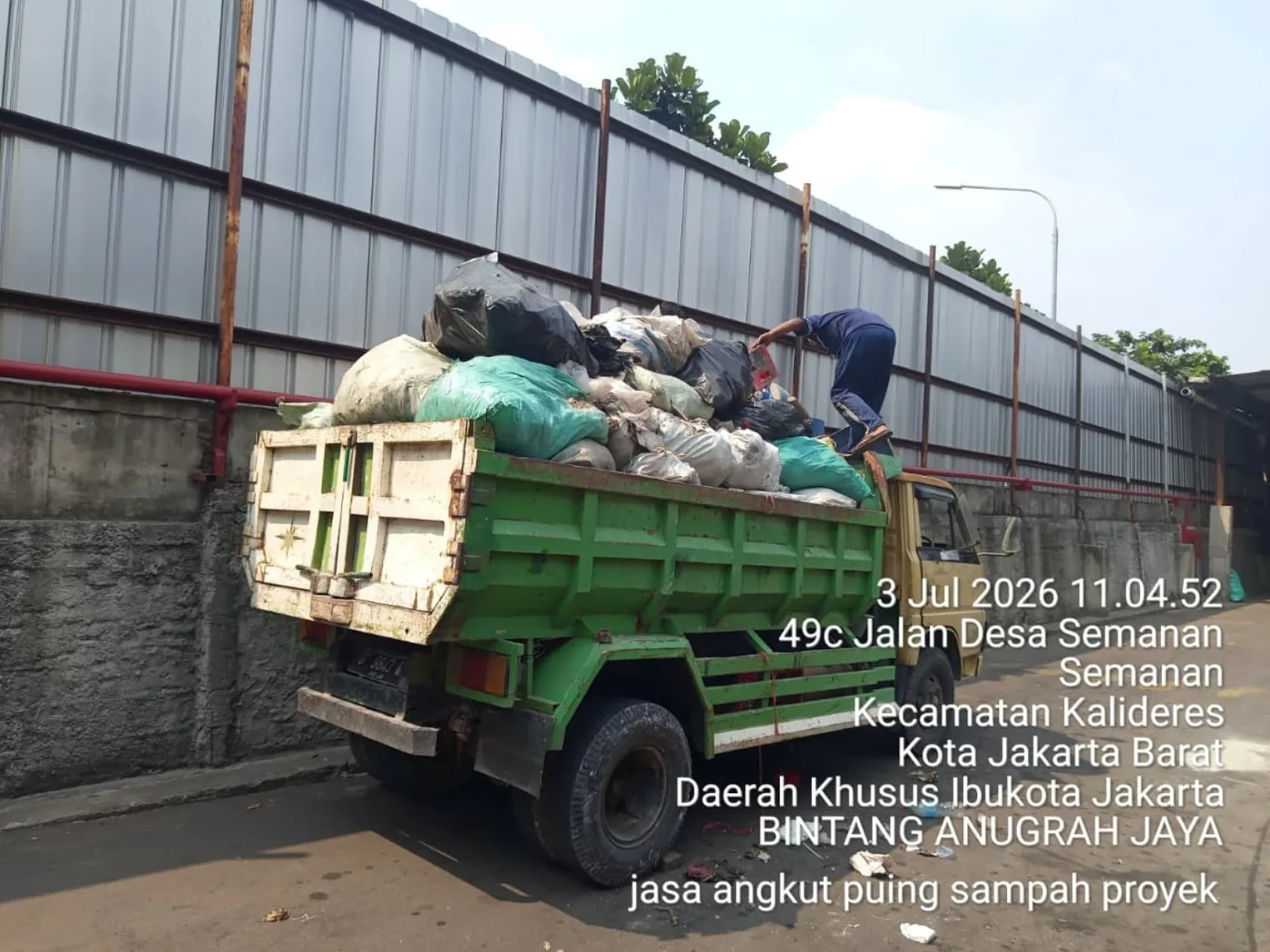Truk hijau mengangkut sampah proyek yang dikemas dalam karung